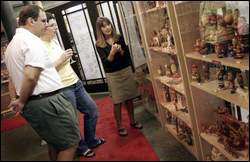 bilde Judi Vaillancourt, right, displays some historic figurines made from chocolate and ice cream molds to Lexington collectors David LaFauci and Claudia Cassettari at the Vaillancourt Folk Art Museum’s recent grand opening. (MICHELLE SHEPPARD PHOTOS)