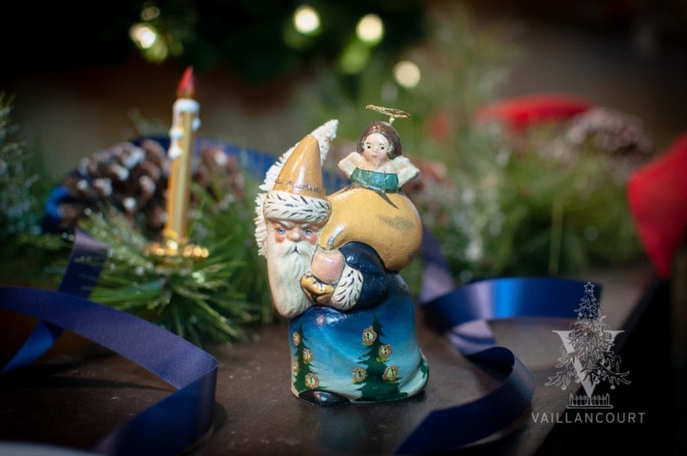 This hand-painted chalkware Santa is seen carrying a sweet angel from his beg. His coat, boasting beautiful nighttime blues, is adorned with trees embellished with candles that are lit to celebrate St. Lucia.