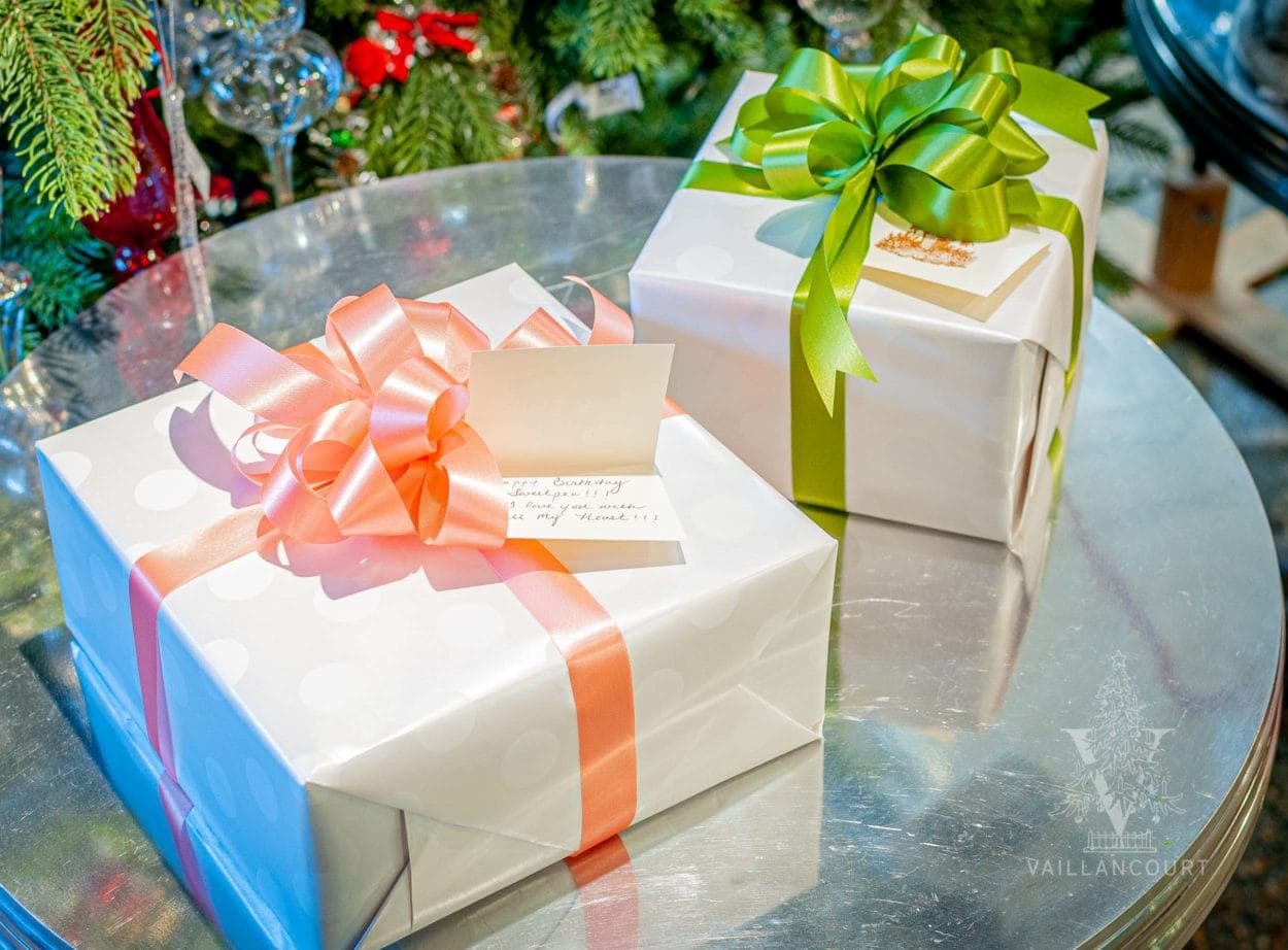 Two gifts, beautifully gift wrapped in white paper. One box with a beautiful green ribbon and bow and the second in pink. Displaying a hand-written gift tag with a personalized message for the gift recipient.
